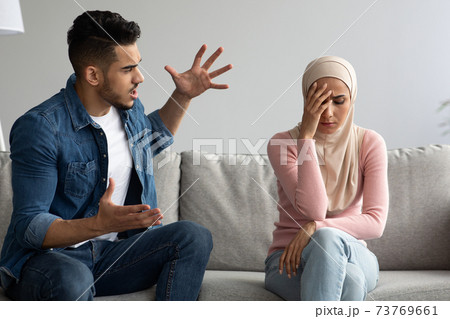 Fighting muslim man and woman sitting on couch at home Fighting muslim man and woman sitting on couch at home 73769661