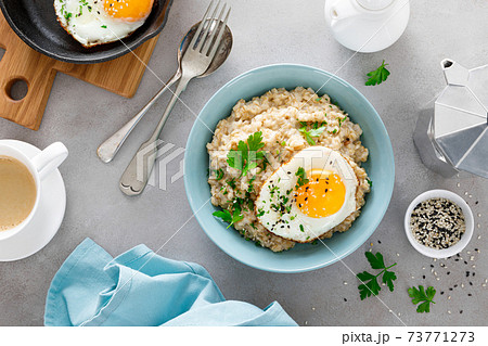 Savoury oatmeal with fried eggs sunny side up for breakfast Savoury oatmeal with fried eggs sunny side up for breakfast 73771273