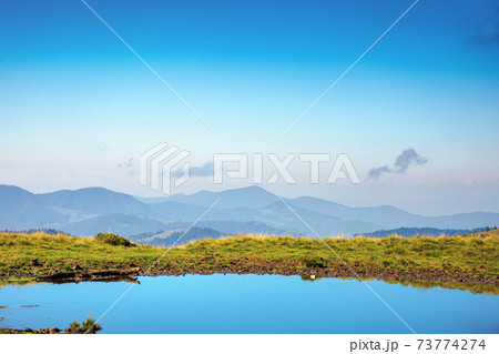 pond on the mountain meadow. beautiful summer landscape in morning light. grass on the hills. ridge in the distance pond on the mountain meadow. beautiful summer landscape in morning light. grass on the hills. ridge in the distance 73774274