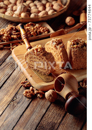 Walnut cake, nuts and wooden kitchen utensils on a wooden table. Walnut cake, nuts and wooden kitchen utensils on a wooden table. 73774644
