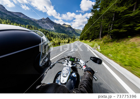 POV of motorbiker holding steering bar, riding in Alps 73775396