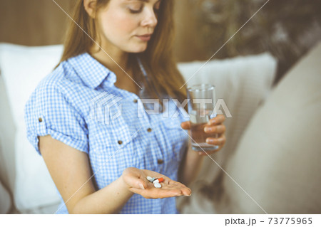 Close-up woman holding pills time to take medications, cure for headache, high blood pressure or cholesterol level remedy pain killer drugs. Medicine concept Close-up woman holding pills time to take medications, cure for headache, high blood pressure or cholesterol level remedy pain killer drugs. Medicine concept 73775965