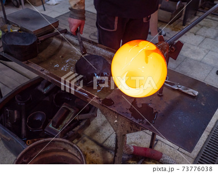 Man Hands Shaping hot glass art piece with wooden tool Man Hands Shaping hot glass art piece with wooden tool 73776038