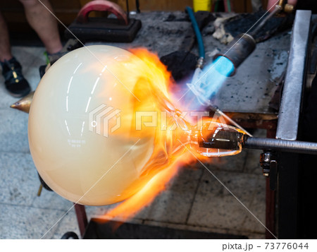 Manual glassblowing process. Man Working on a big glass art Manual glassblowing process. Man Working on a big glass art 73776044