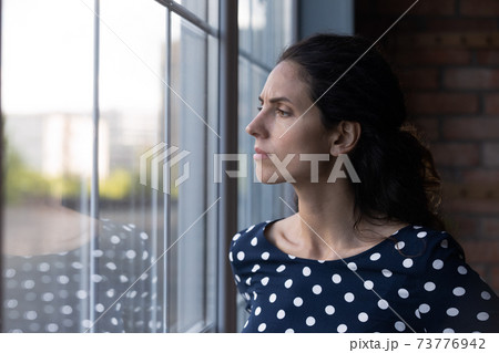 Unhappy woman look in window feeling worried Unhappy woman look in window feeling worried 73776942
