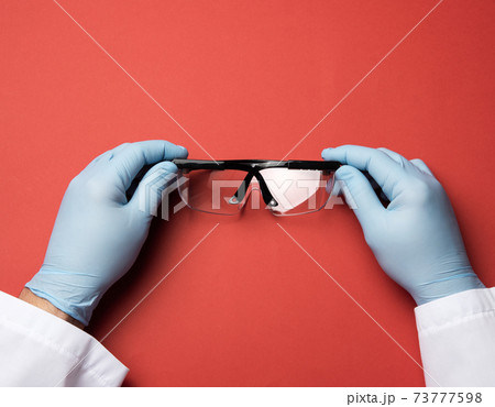 hand hold protective plastic glasses on a red background hand hold protective plastic glasses on a red background 73777598