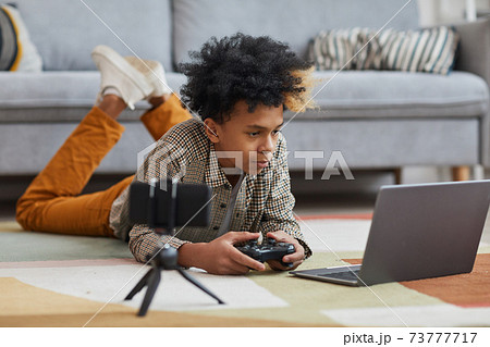 African-American Boy Playing Videogames on Floor African-American Boy Playing Videogames on Floor 73777717