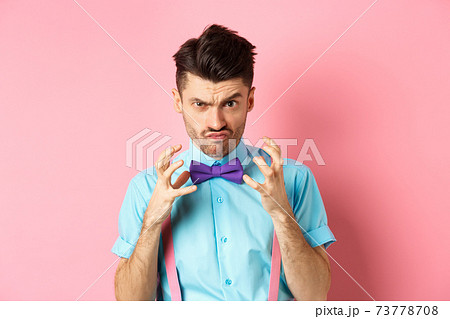 Image of angry guy in bow-tie gonna strangle someone, raising hands up and looking mad or pissed-off, feeling furious, standing on pink background 73778708