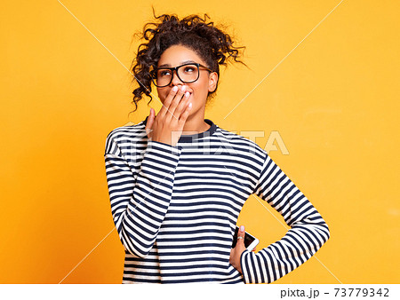 Astonished ethnic woman covering mouth 73779342