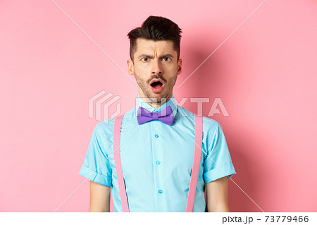 Shocked and offended young man frowning, looking at someone rude, standing insulted on pink background 73779466