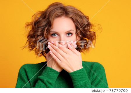 Shocked young female covering mouth Shocked young female covering mouth 73779700
