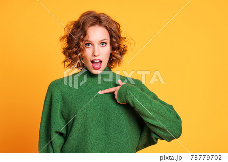 Astonished young woman pointing at chest 73779702