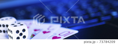 Online gaming platform, casino and gambling business. Cards and dice on laptop keyboard, toned in blue Online gaming platform, casino and gambling business. Cards and dice on laptop keyboard, toned in blue 73784209