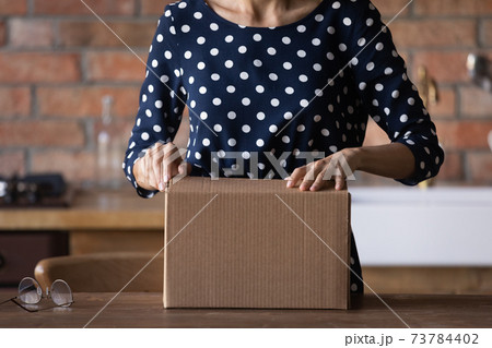 Close up of woman unpack box shopping online from home 73784402