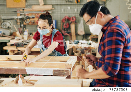 Carpenter measuring wooden planks 73787503