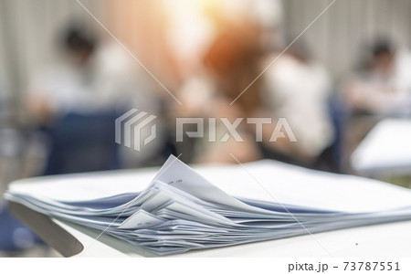 Exam answer sheet pile, blurry application document paperwork stack on office work table in examination room or classroom with blur education background school class university students taking test 73787551