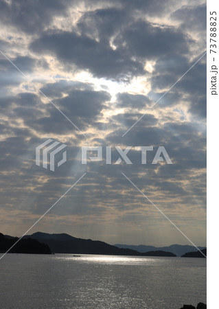 雲間から射す光がスポットライトの様に海面を照らしている風景の写真