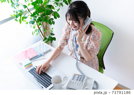 電話応対するワンピースを着た若い女性の写真素材