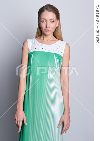 Beautiful model in light airy sleeveless sundress posing over gray background 73791971