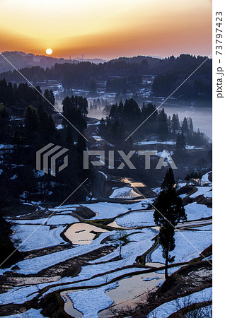 まだ雪の残る十日町市蒲生の棚田に赤い朝日が昇るの写真素材