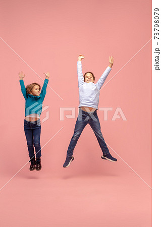 Happy children isolated on coral pink studio background. Look happy, cheerful, sincere. Copyspace. Childhood, education, emotions concept 73798079
