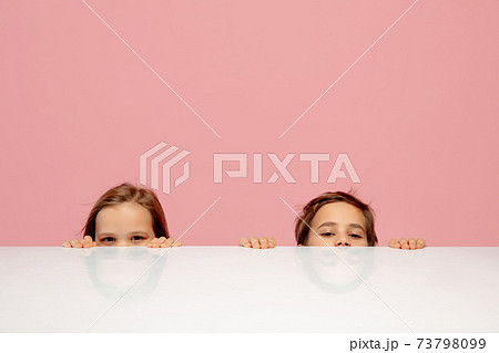 Happy children isolated on coral pink studio background. Look happy, cheerful, sincere. Copyspace. Childhood, education, emotions concept Happy children isolated on coral pink studio background. Look happy, cheerful, sincere. Copyspace. Childhood, education, emotions concept 73798099