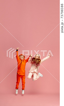 Happy children isolated on coral pink studio background. Look happy, cheerful, sincere. Copyspace. Childhood, education, emotions concept 73798386