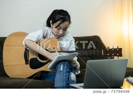 Happy asian teen girl is practicing composing a song,trying to write a new music in her diary,female people relaxing time,hobby,lifestyle,inspiration,creative musician enjoy write making up a lyrics 73798496