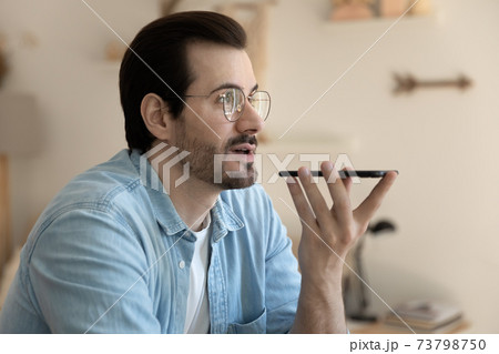 Confident young man communicating with friend by loud speaker Confident young man communicating with friend by loud speaker 73798750