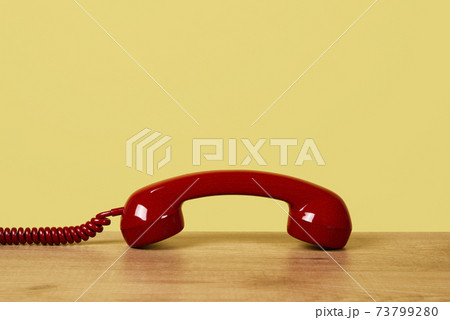 red telephone off the hook on a yellow background 73799280