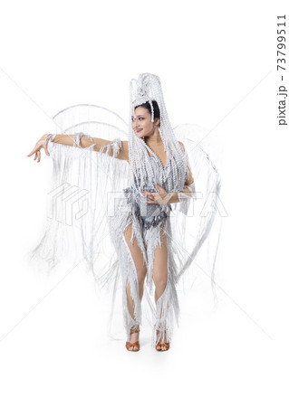 Beautiful young woman in carnival, stylish masquerade costume with feathers dancing on white studio background. Concept of holidays celebration, festive time, fashion 73799511
