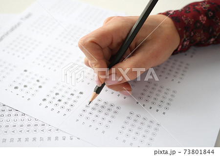 Female hand holds pencil and marks answers to test Female hand holds pencil and marks answers to test 73801844