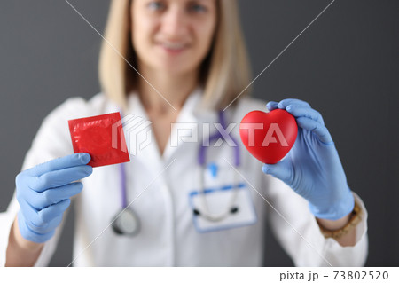 Doctor holds condom and heart in his hand Doctor holds condom and heart in his hand 73802520