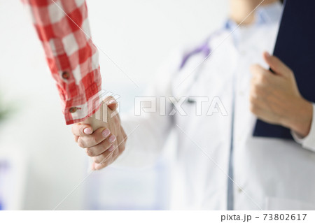 Doctor holds clipboard shakes hands with patient 73802617
