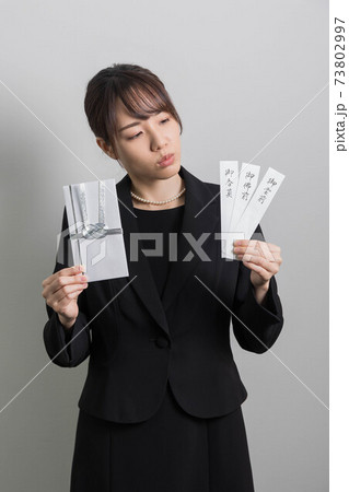 不祝儀袋を持って考え事をする喪服の若い女性 【葬儀】 不祝儀袋を持って考え事をする喪服の若い女性 【葬儀】 73802997