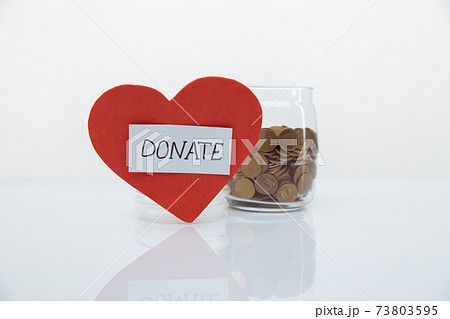Red heart with DONATE word near glass ban with coins close-up. Charity and donation concept. Red heart with DONATE word near glass ban with coins close-up. Charity and donation concept. 73803595