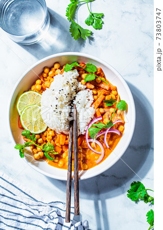 Vegan chickpea curry with rice and cilantro in white bowl, white marble background. Indian cuisine concept. 73803747