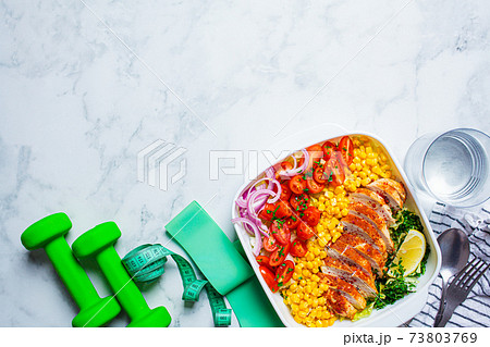 Fitness food concept. Diet chicken salad with vegetables and sports equipment on white marble background, copy space. Fitness food concept. Diet chicken salad with vegetables and sports equipment on white marble background, copy space. 73803769