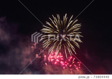 Bright red fireworks lights in the night sky. Small city celebrates new year with colorful fireworks Bright red fireworks lights in the night sky. Small city celebrates new year with colorful fireworks 73804440