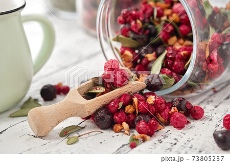 Glass jar of fruit tea with apples, orange, red and black currant berries close up on white kitchen table. Glass jar of fruit tea with apples, orange, red and black currant berries close up on white kitchen table. 73805237