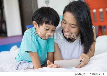 close up of happy mother and her son Taking pictures or selfie or video call or relatives in a bed. Concept of new generation, family, parenthood, authenticity, connection. 73806701