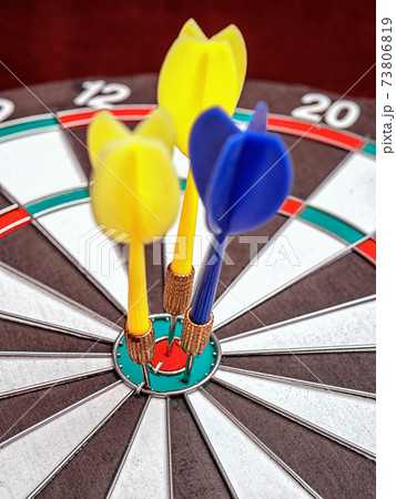 Side view of a dartboard with three darts in the bull's eye. Well-aimed dart throwing. Triple bull's-eye hit. Successful attempts. 73806819