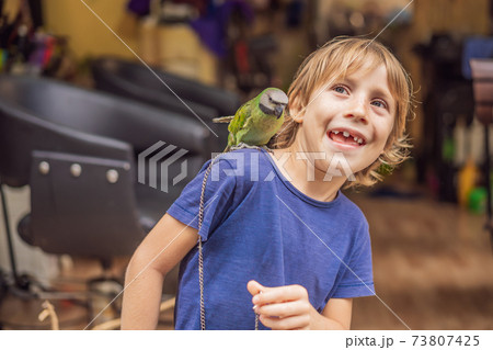 Kid playing with his pet green parrot Kid playing with his pet green parrot 73807425