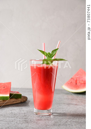 Glass of watermelon cocktail garnish mint on grey background. Close up. Vertical. Glass of watermelon cocktail garnish mint on grey background. Close up. Vertical. 73807441