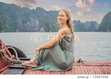 Attractive woman in a dress is traveling by boat in Halong Bay. Vietnam. Travel to Asia, happiness emotion, summer holiday concept. Picturesque sea landscape. Ha Long Bay, Vietnam 73807489