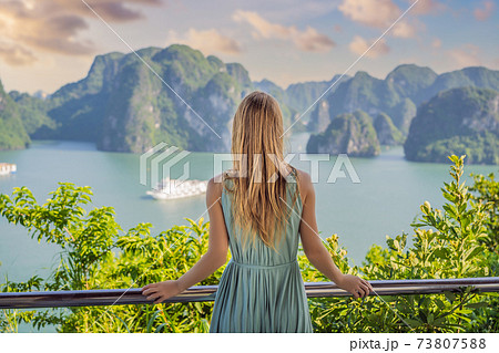Attractive woman in a dress is traveling in Halong Bay. Vietnam. Travel to Asia, happiness emotion, summer holiday concept. Picturesque sea landscape. Ha Long Bay, Vietnam 73807588