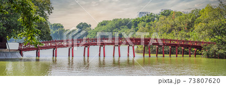 BANNER, LONG FORMAT The Red Bridge in public park garden with trees and reflection in the middle of Hoan Kiem Lake in Downtown Hanoi. Urban city at sunset, Vietnam. Cityscape background 73807620