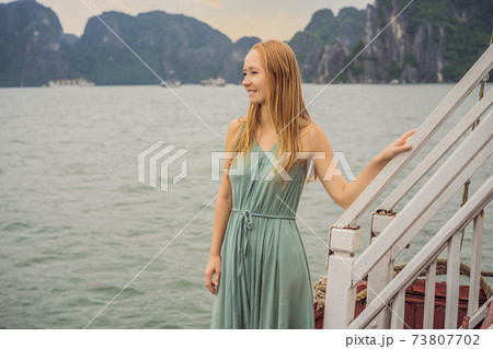 Attractive woman in a dress is traveling by boat in Halong Bay. Vietnam. Travel to Asia, happiness emotion, summer holiday concept. Picturesque sea landscape. Ha Long Bay, Vietnam Attractive woman in a dress is traveling by boat in Halong Bay. Vietnam. Travel to Asia, happiness emotion, summer holiday concept. Picturesque sea landscape. Ha Long Bay, Vietnam 73807702