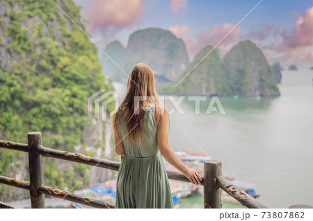 Attractive woman in a dress is traveling in Halong Bay. Vietnam. Travel to Asia, happiness emotion, summer holiday concept. Picturesque sea landscape. Ha Long Bay, Vietnam Attractive woman in a dress is traveling in Halong Bay. Vietnam. Travel to Asia, happiness emotion, summer holiday concept. Picturesque sea landscape. Ha Long Bay, Vietnam 73807862