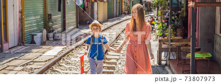BANNER, LONG FORMAT Mother and son travelers walk around railway paths which go through residential area in Hanoi city. Hanoi Train Street is a famous tourist destination. Vietnam reopens after 73807973